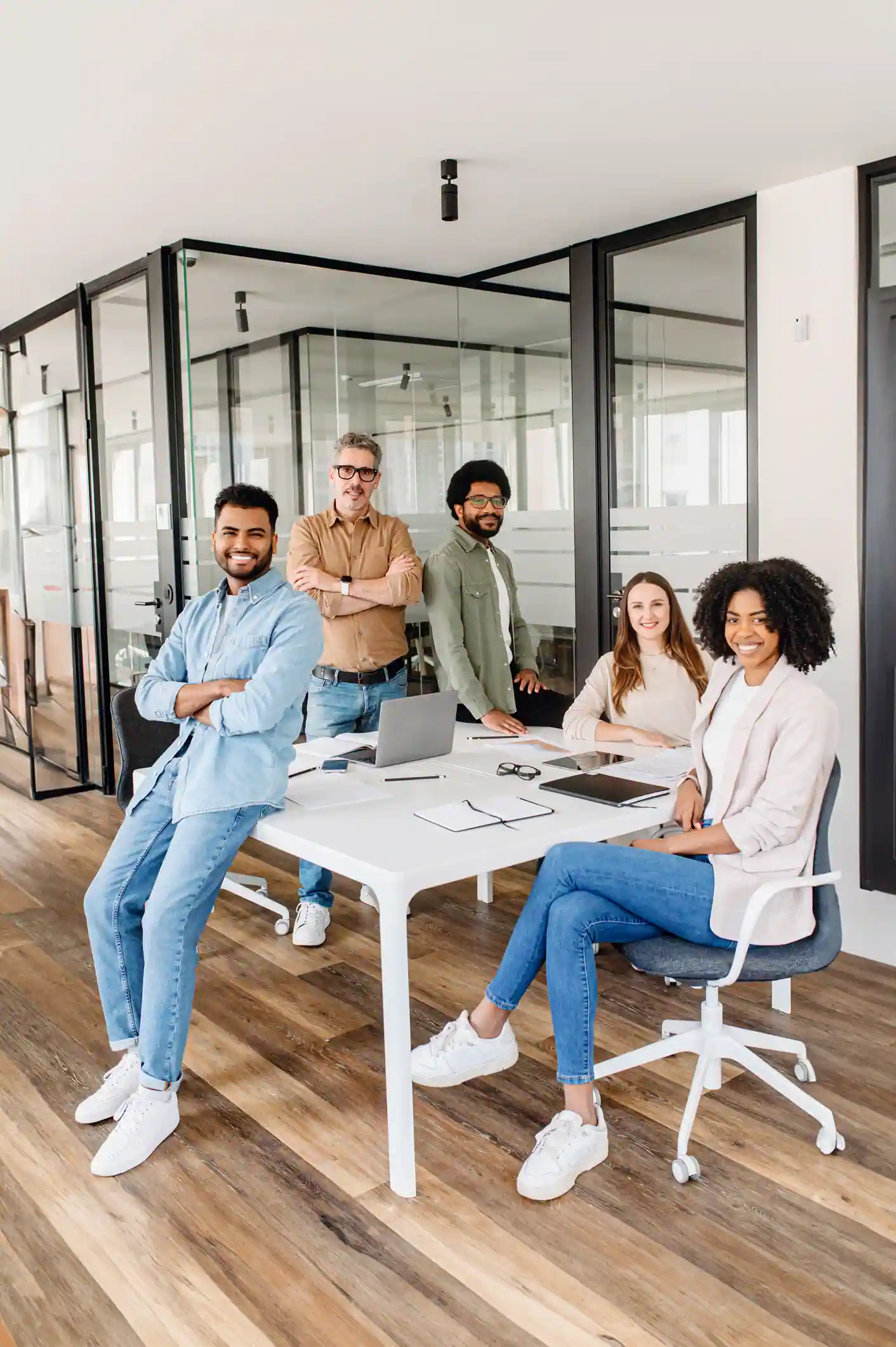 A diverse group of five colleagues beams with pride in their office